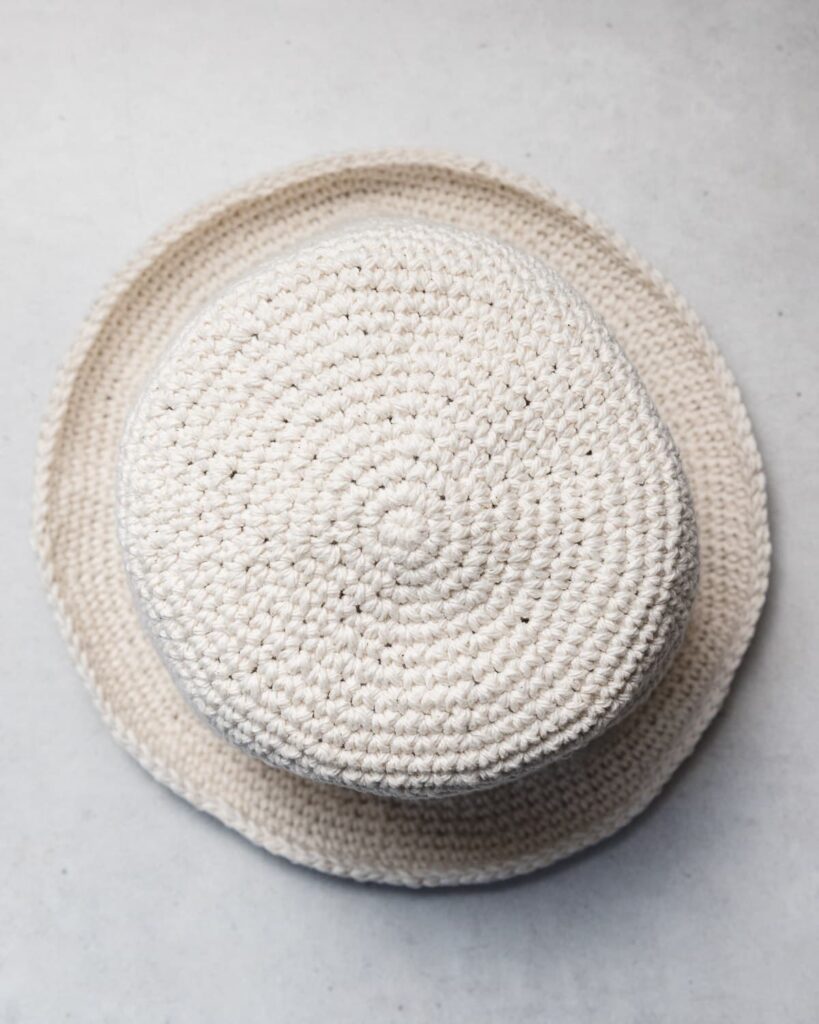 pin image with the text how to crochet bucket hat on a background of a woman wearing a white bucket hat