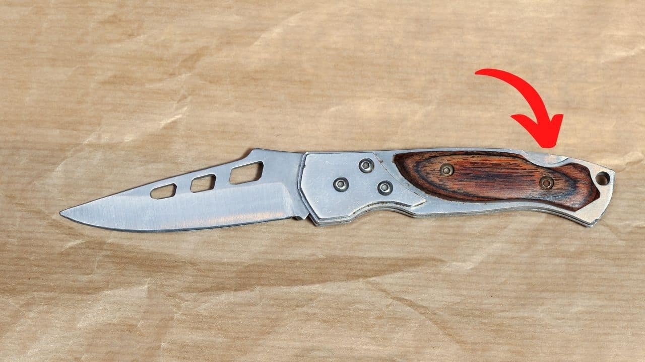 lockback folding knife with a red arrow pointing to the release