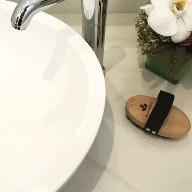 Prana Brush dry brush placed on a bathroom counter beside sink