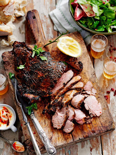 Image of grilled lamb thighs, spread with butter on a wooden cutting board