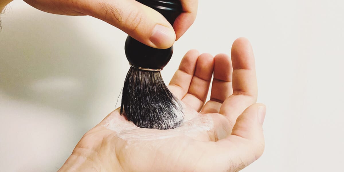 lathering beard brush with shaving cream in palm of hand