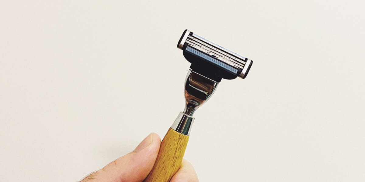 man holding bamboo shaving razor with razor blade