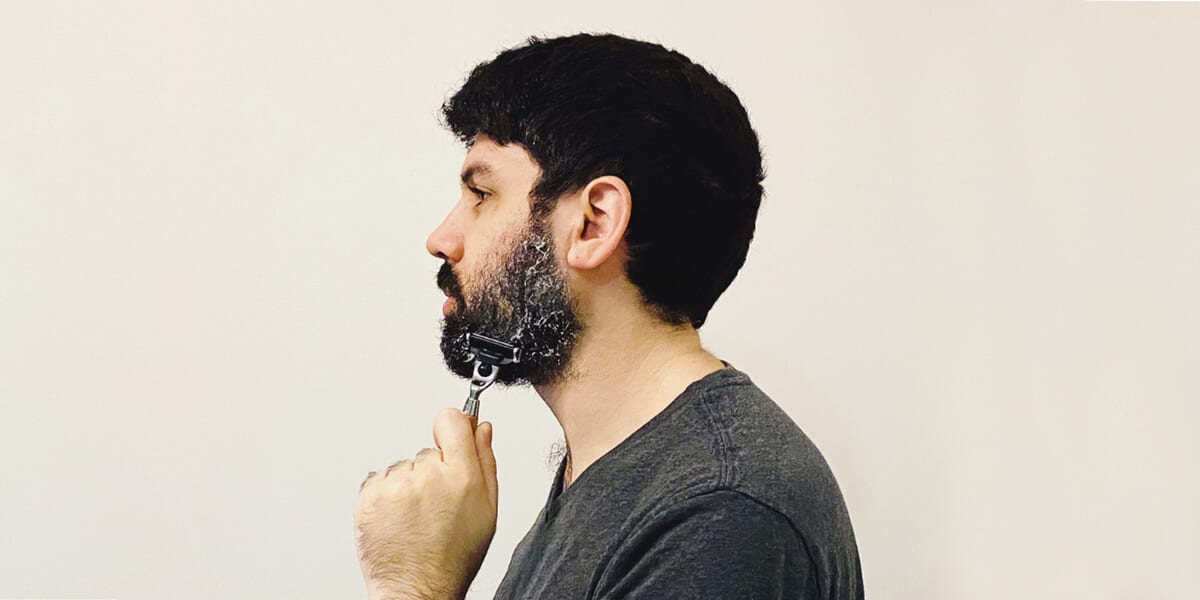 man shaving beard with razor and shaving cream