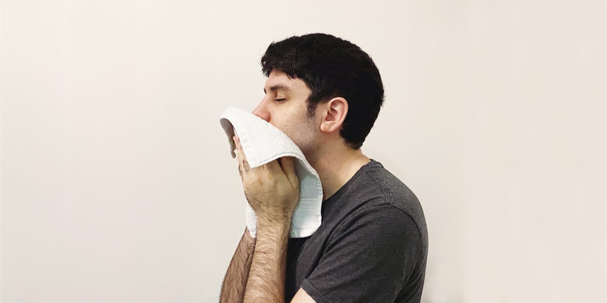 man wiping face with washcloth