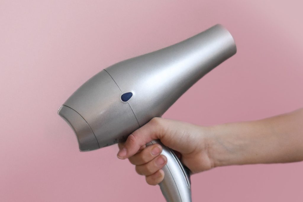 person holding a gray hair dryer 973406