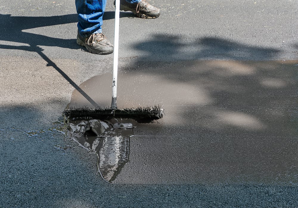 The man sealed the driveway before it rained, letting it dry for at least 4-8 hours before it rained.