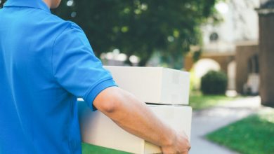 Delivery service courier standing in front of the house with box
