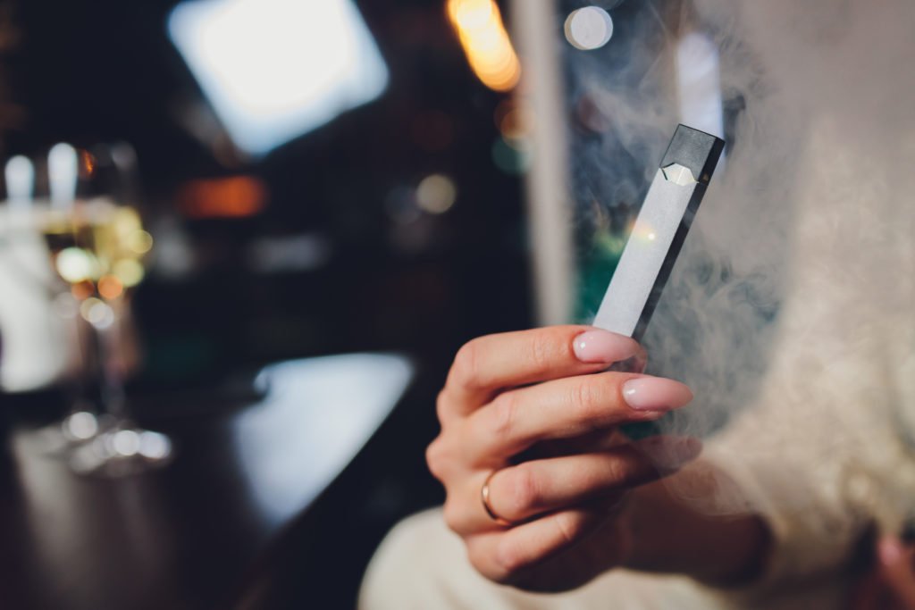 Hand holding a gray electronic cigarette.