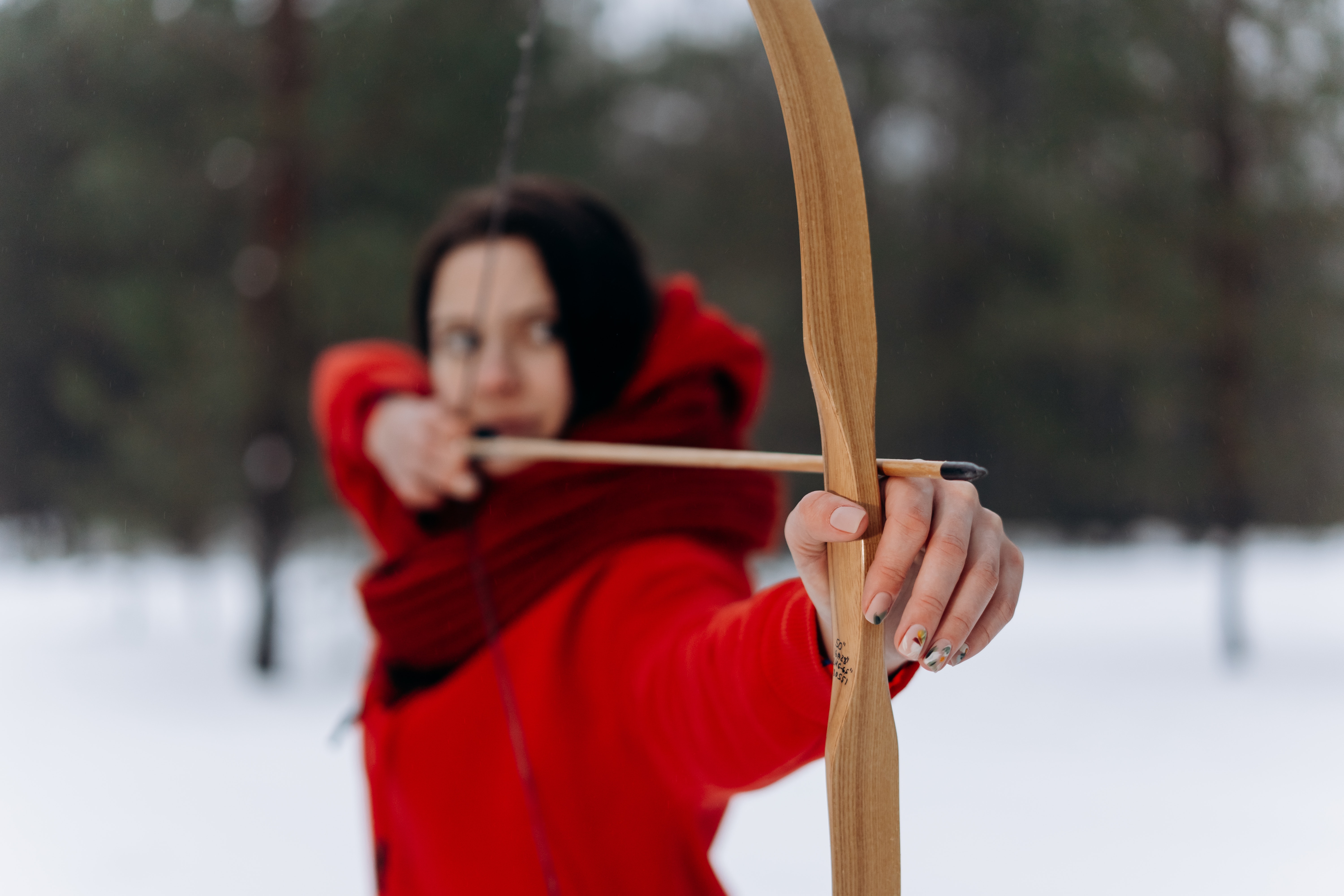Selective focus of woman in red coat draw bow
