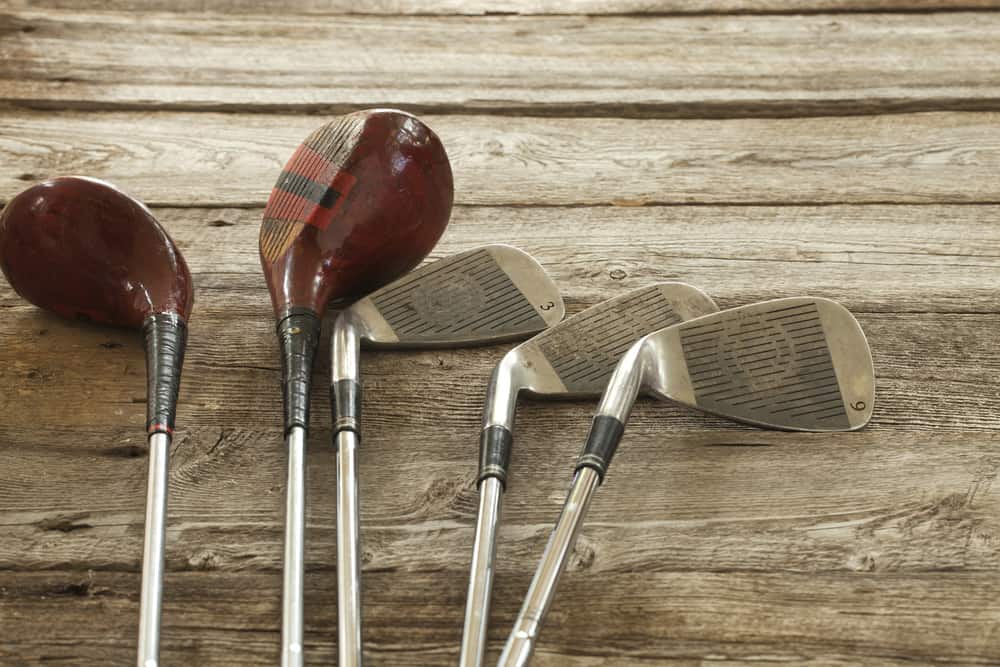 Old golf clubs on rough wooden surface